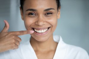 Young woman pointing at her beautiful smile.