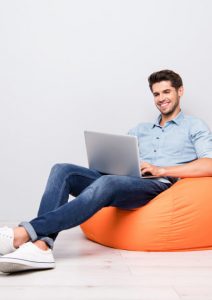 Man sitting on an orange bean bag searching for dentists